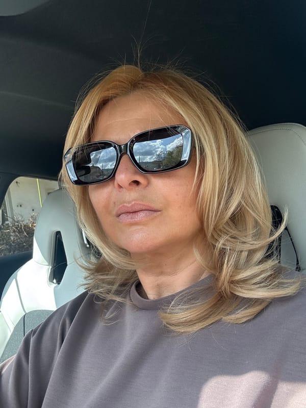 Blonde woman in sunglasses photographed with spring tulips