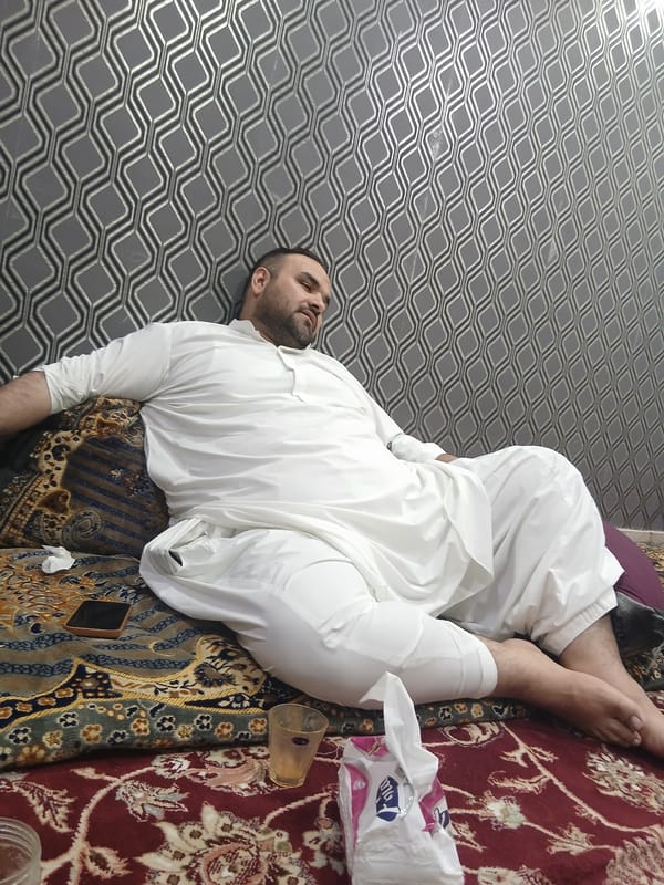 Man rests on carpet with personal items in Quetta