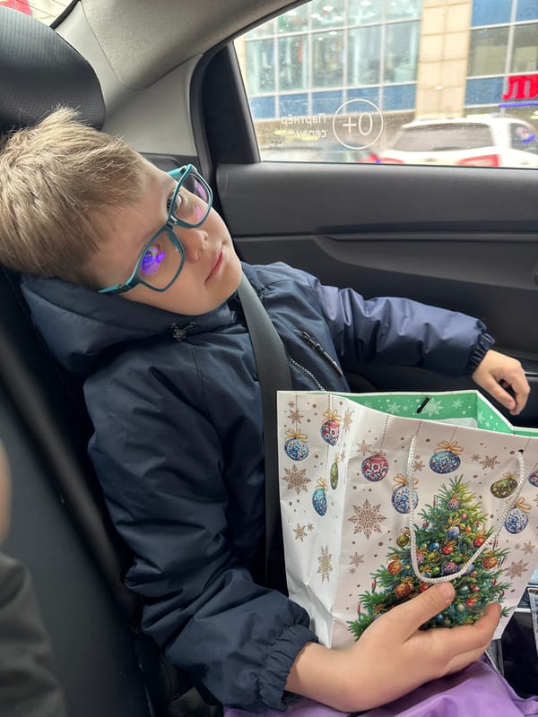 Boy examines Christmas gift bag in car backseat in Perm