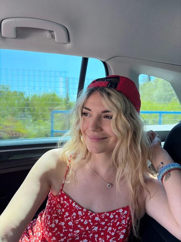 Woman in red cap photographed smiling in car, Tivat