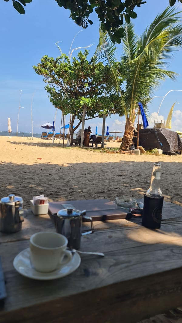 A Bali beach morning: jukung boats, kite surfers, and beach loungers