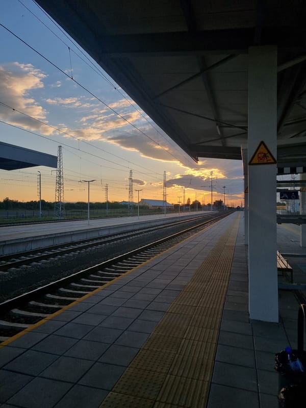 Evening railway journey captured through platform and countryside views