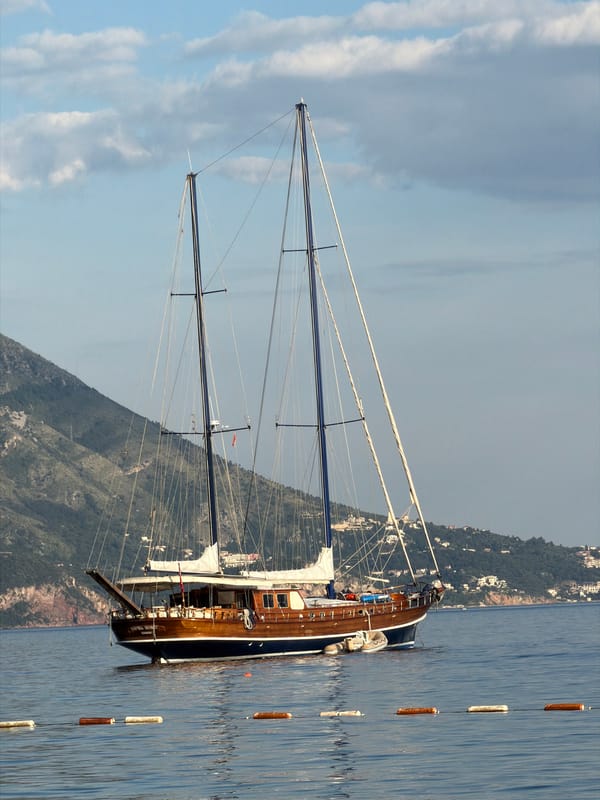 Sailboats and beachgoers enjoy calm afternoon in Budva, Montenegro