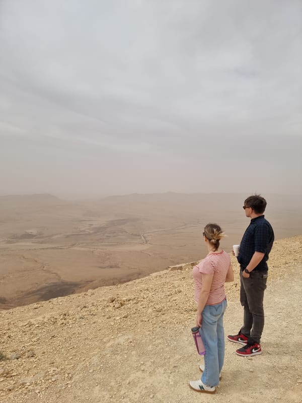 Two visitors observe desert landscape at Mitzpe Ramon overlook