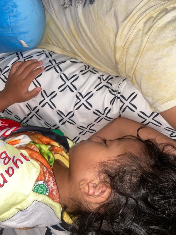 Child sleeps peacefully beside adult in Indonesian home