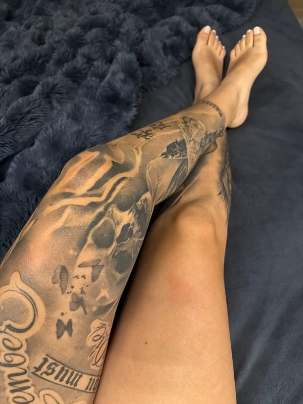 Tattooed individual rests on dark surface in casual moment