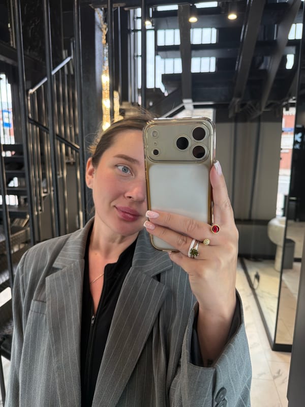 Woman takes selfies in indoor space with stairs, chandelier