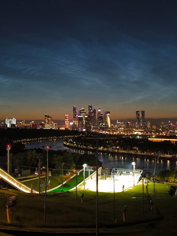Illuminated ski jump at night with Moscow skyline behind it
