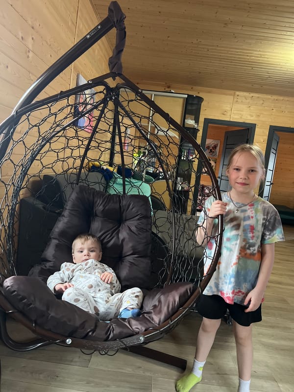 Children playing indoors with hanging chair in Protasy home
