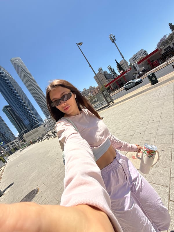 Woman takes selfie on Ramat Gan sidewalk amid urban backdrop