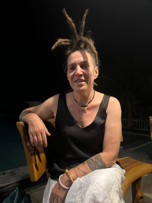 Person with dreadlocks relaxes outdoors with phone, rum in Mũi Né