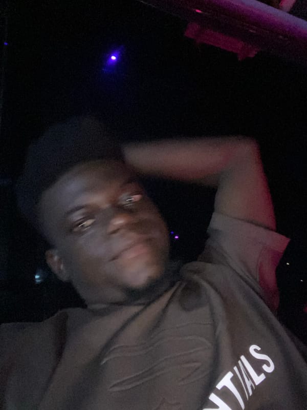 Person in brown hoodie photographed near purple light source