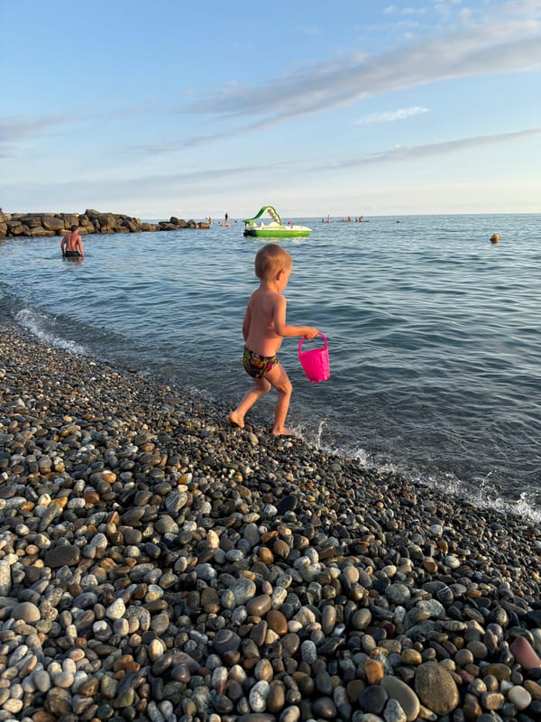 Kids and selfies on a Sochi pebble beach at sunset
