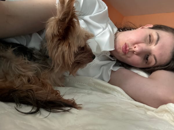 Woman takes selfie with small dog on bed
