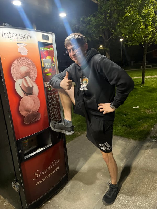 Young man poses with thumbs-up beside outdoor vending machine
