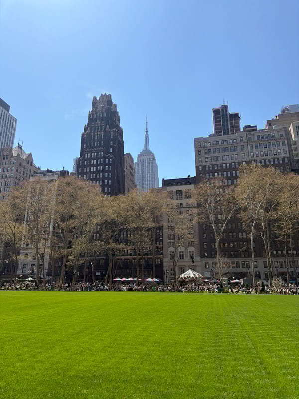 Afternoon crowd gathers at Bryant Park beneath Empire State Building