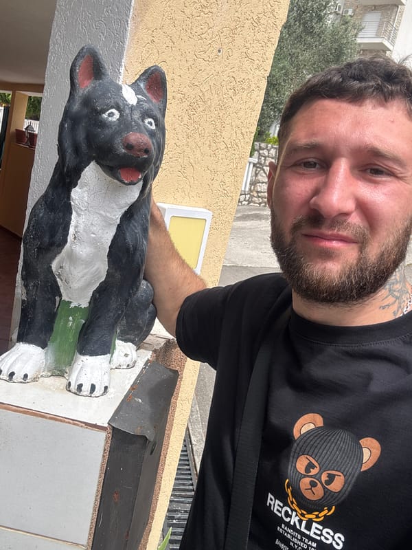 Man poses with dog sculpture in black T-shirt