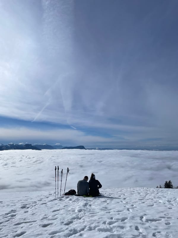 Two people sit on snowy ridge near Les Déserts