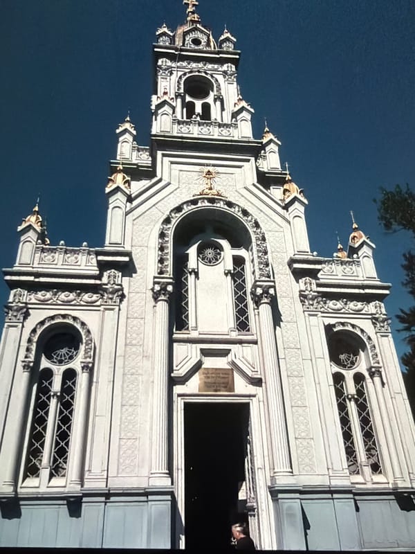 Looking up: ornate stone facade and a contrail-streaked city sky