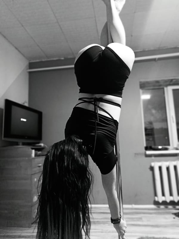 Woman practices pole dancing moves during indoor training session