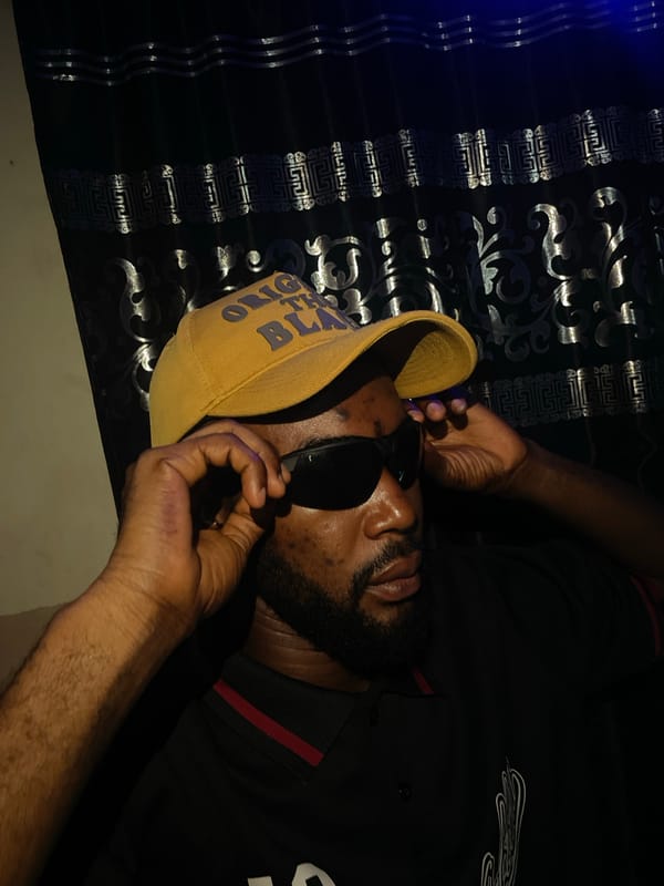 Man in cap and sunglasses rests on bed in Lokoja