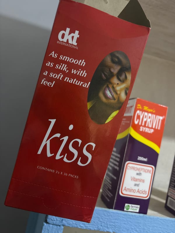 Woman uses phone near pharmacy shelf in Nigerian city