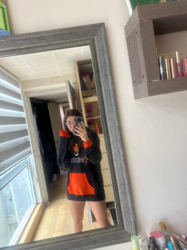 Mirror selfie in a Puebla bedroom, black hoodie with flame graphic.