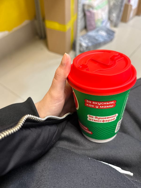 Person with Russian-text coffee cup observed indoors