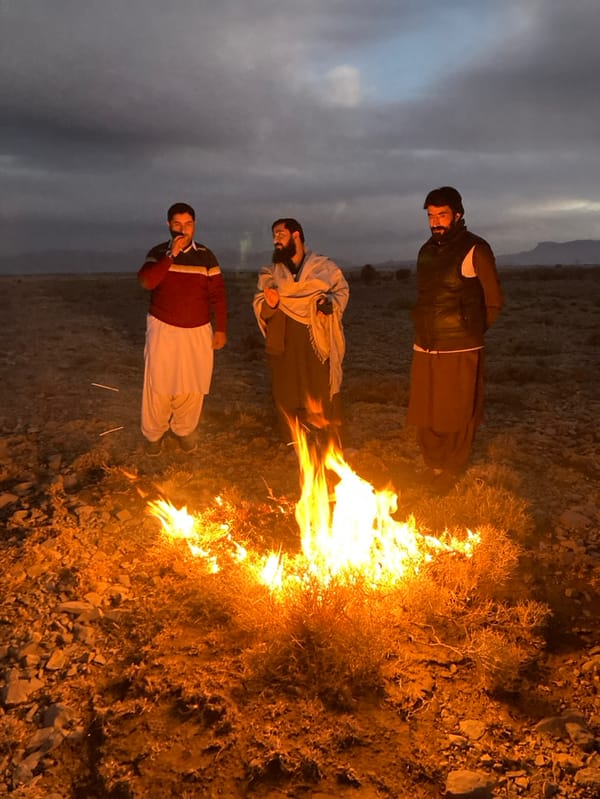 Three men gather around bonfire in rural Pakistan