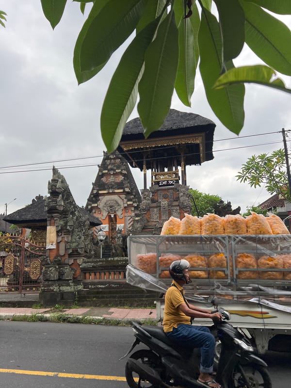 Artisan works metal craft amid bustling Ubud street scene