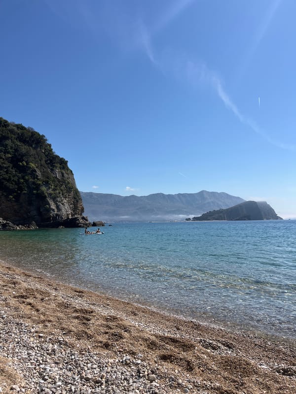 Woman in polka dot dress relaxes on rocks at Budva beach