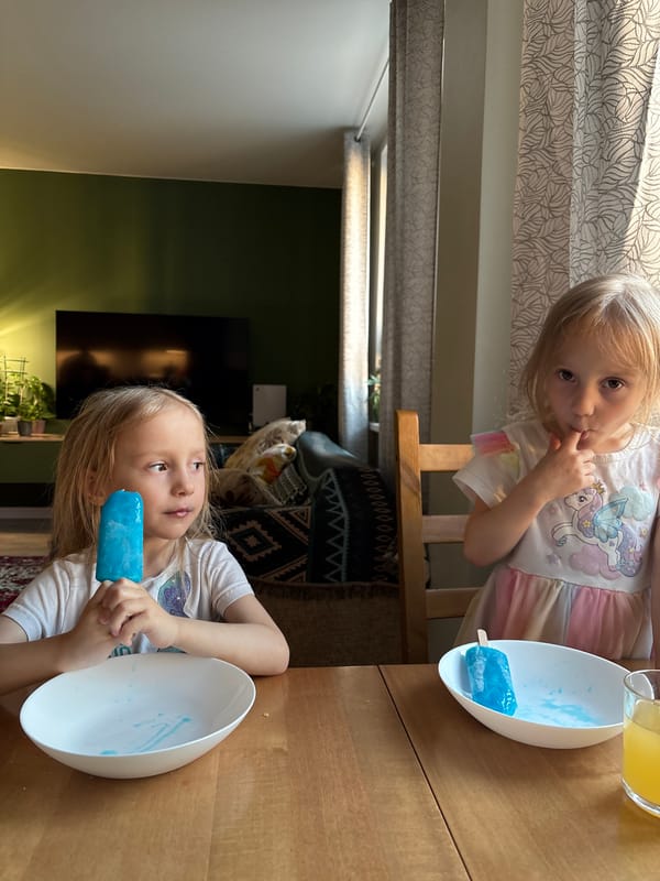Two girls enjoy blue popsicles indoors in Krasnoyarsk