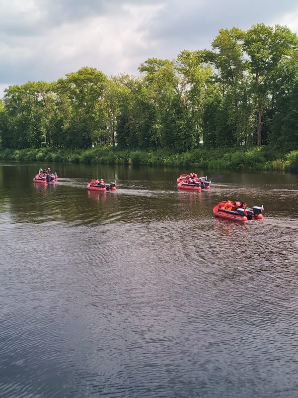 Red inflatable boats travel in convoy down a Russian river