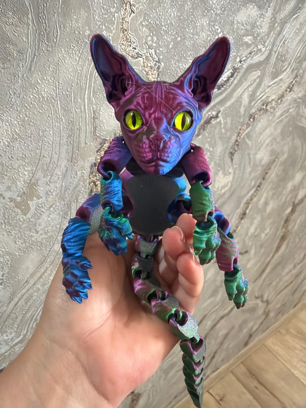 3D printed articulated cat figurines shown up close in hand