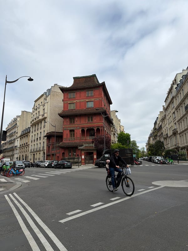 Cyclist crosses street near Chinese pagoda in Paris