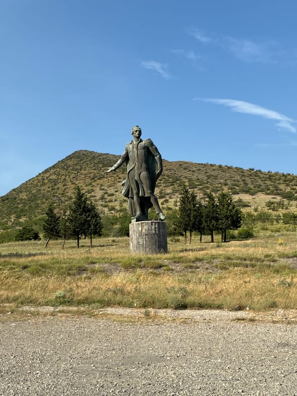 Bronze suited figure on pedestal in rural Georgian field