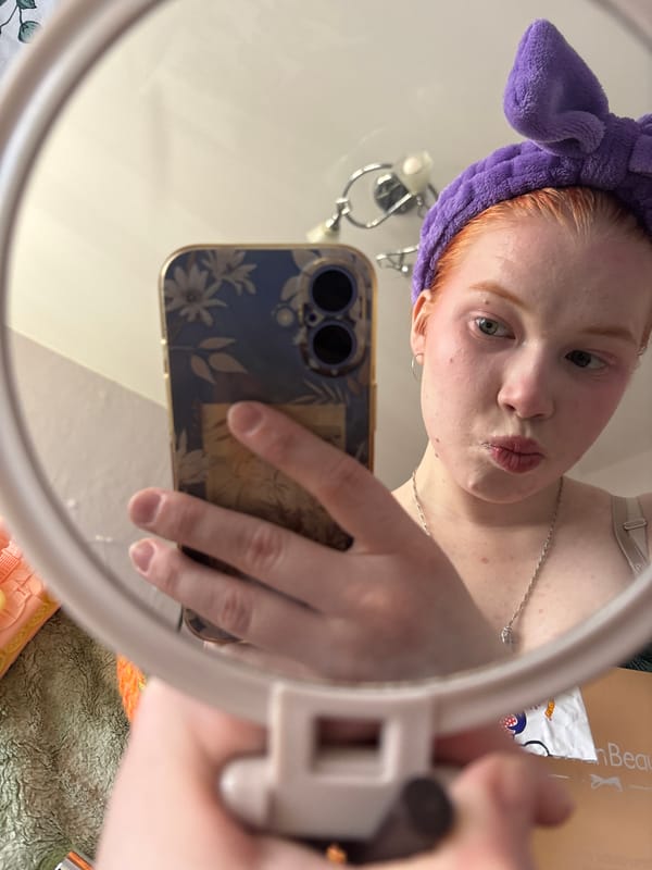 Red-haired person takes selfies with bunny ear headband indoors