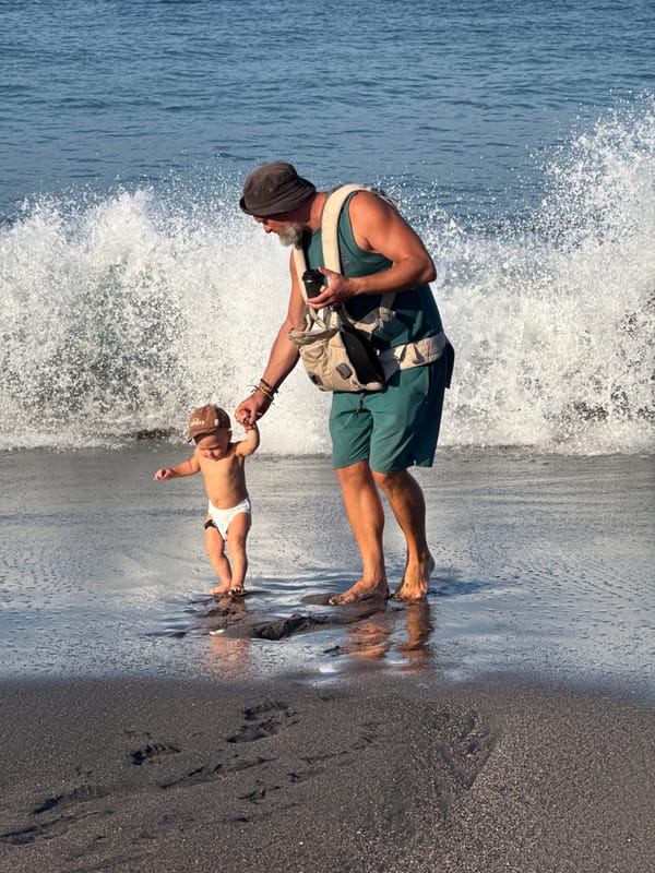 Man carries baby in shallow waters near Mengwi beach