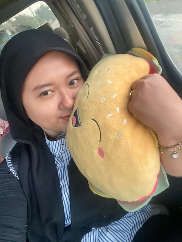 Woman holds burger plush toy in vehicle in Tlasih