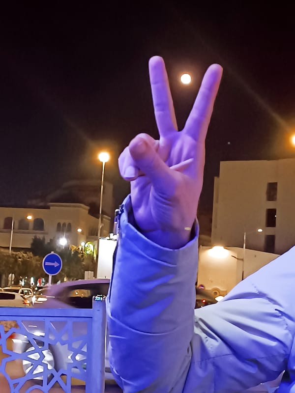 Peace sign gesture captured on Meknes street at night