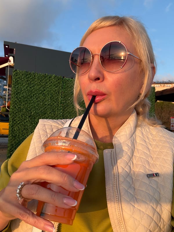 Person enjoys sunset drink at beach during golden hour