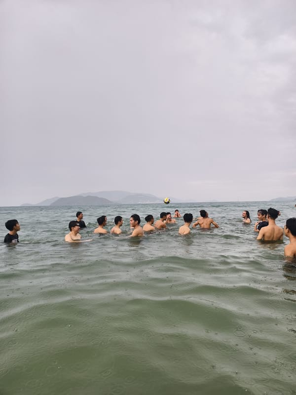 Young men play water volleyball at crowded beach