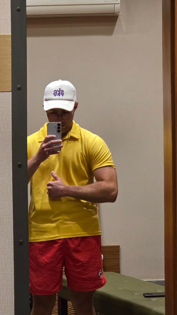 Mirror selfies in a bold yellow polo and purple-lettered hat
