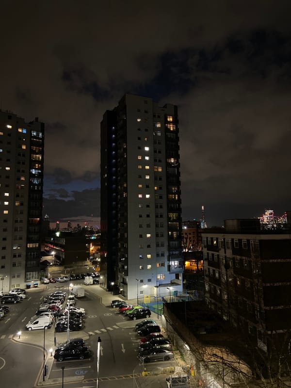 London tower blocks illuminated at night with parking lot