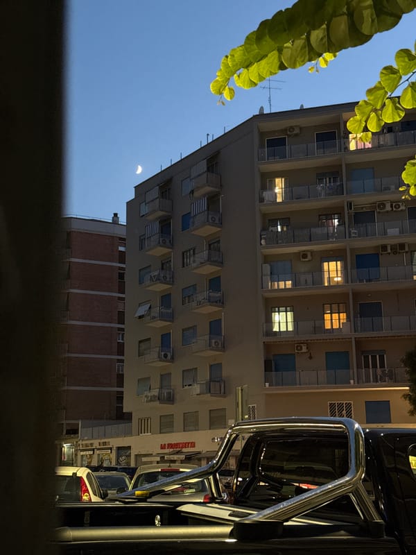 Rome street at dusk, crescent moon over parked pickup truck