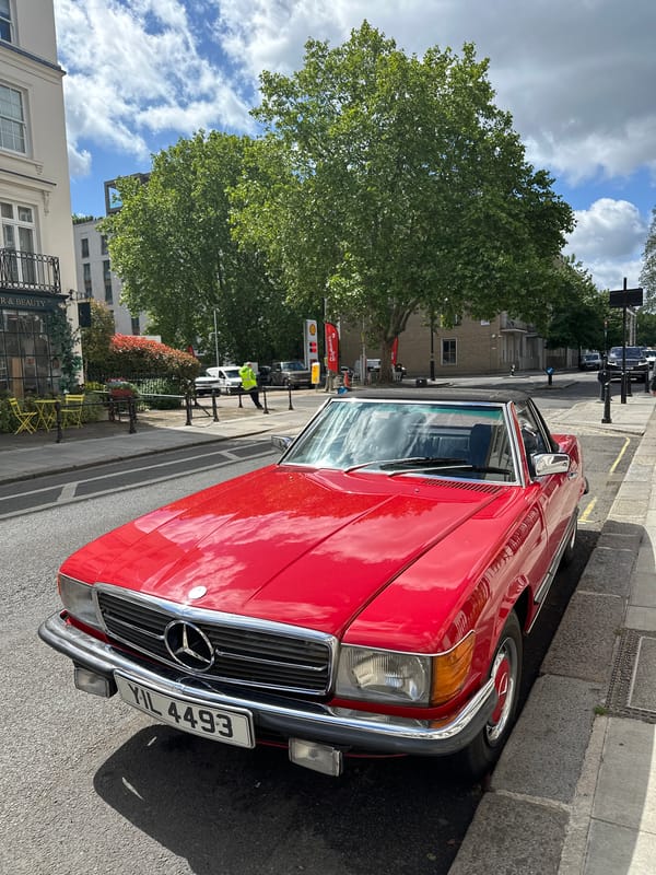 Red Mercedes parked near flower-adorned Bayley shop in London