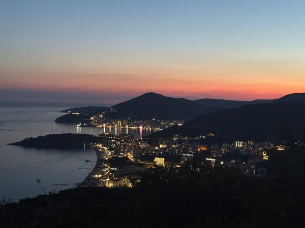 Coastal city glows under a twilight sky from above