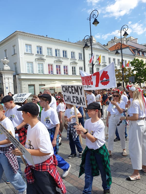Folk dancers and marching band parade through historic Warsaw street