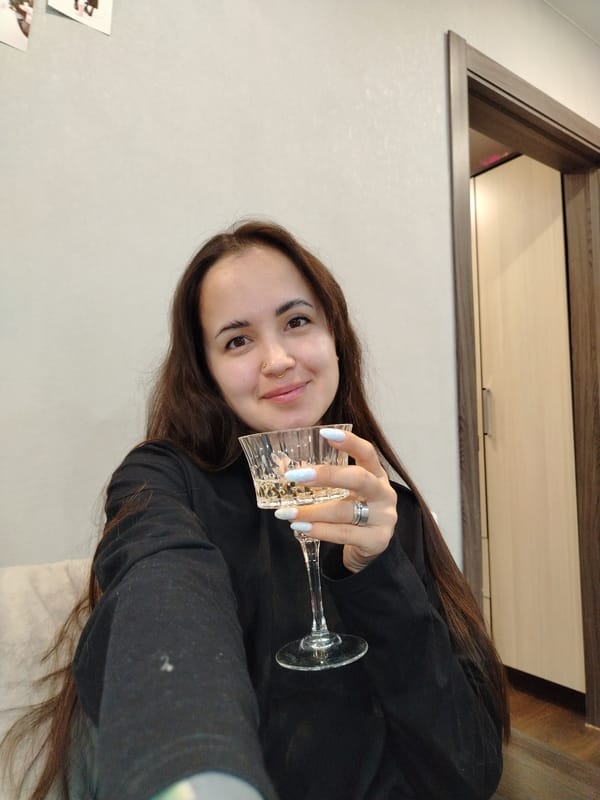 Woman enjoys wine, poses playfully indoors in Noviy, Russia