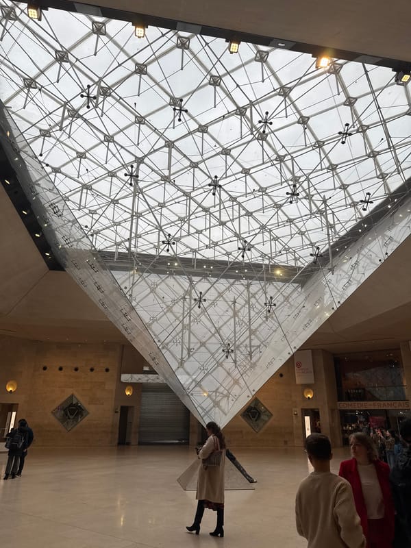 Visitors document iconic Louvre Museum pyramid and entrance in Paris